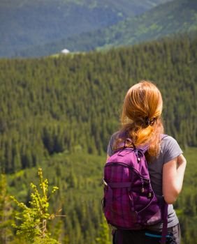 girl hiker with a backpack standing on the background of mountains and forests. Ukrainian landscape.

