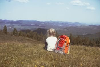 girl hiker with a backpack sitting on the background of mountains and forests. Vorokhta - Ukrainian landscape.
