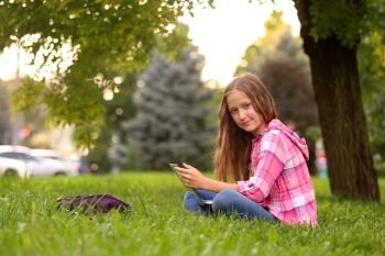Girl with notebook sitting at  the grass
