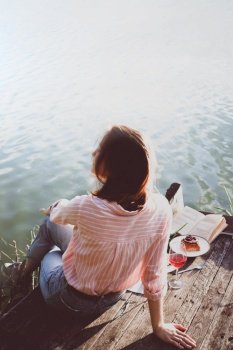 girl enjoying picnic on a wooden pier on a shiny summer river shore
