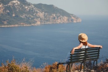 girl tourist sitting on a bench at  the observation deck and looks at the sea and a beautiful landscape, Corfu Island in Greecethe sea 
