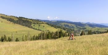 Motorcyclist on Carpathian Mountainss, extreme sport, active lifestyle, adventure touring concept. Motorcyclist moves down the slope of the Carpathian Mountains