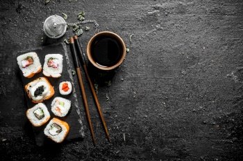 Various Japanese rolls with soy sauce and chopsticks. On black rustic background. Various Japanese rolls with soy sauce and chopsticks.