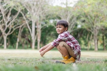 A boy childs arms raised with enjoy on the lawn and wearing hiking shose is over size.Child having fun in summer.