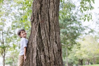 The boy spread his arms to measure the size of a large tree.