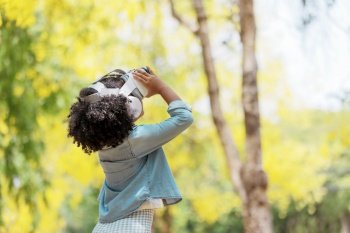 Cool millennial child exploring space with virtual reality glasses at outdoor	