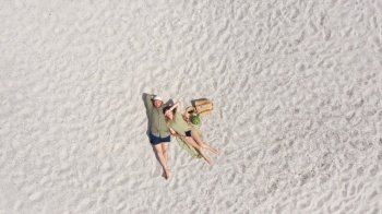 Aerial view of a young couple lying on the white sand. man and woman spend time together and travel through the desert.. Aerial view of a young couple lying on the white sand. man and woman spend time together and travel through the desert