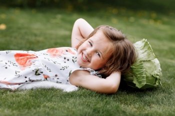 cute little girl is laughing and lying on the grass with the cabbage . happy childhood. cute little girl is laughing and lying on the grass with the cabbage . happy childhood.
