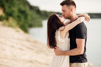 Romantic couple is kissing outdoors. elegant and stylish woman and man in love are walking along the lake. Happy moments together. love story.. Romantic couple is kissing outdoors. elegant and stylish woman and man in love are walking along the lake. Happy moments together. love story
