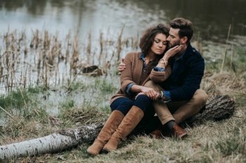 caucasian couple in love in autumn nature. Young bearded man and curly woman are hugging on the shore of a lake. caucasian couple in love in autumn nature. Young bearded man and curly woman are hugging on the shore of a lake.