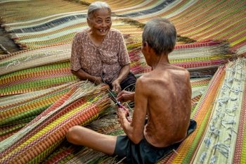 Top view of old Vietnamese lover craftsman making the traditional vietnam mats with happiness action in the old traditional village at dinh yen, dong thap, vietnam, tradition artist concept