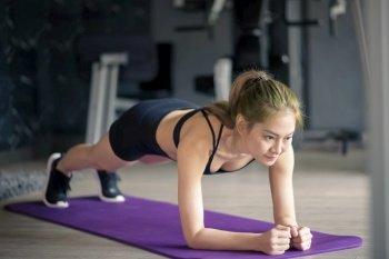 A happy beautiful woman is doing yoga plank on mat at the gym, concept of healthy lifestyle, sports, training, wellness, and sport. . Happy beautiful woman is doing yoga plank on mat at the gym, concept of healthy lifestyle, sports, training, wellness, and sport. 
