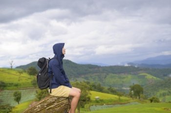 A traveling man enjoying and relaxing over beautiful green mountain view in rain season, Tropical climate.