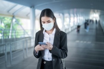 Young business woman with face mask  is standing on metro platform using smart. 