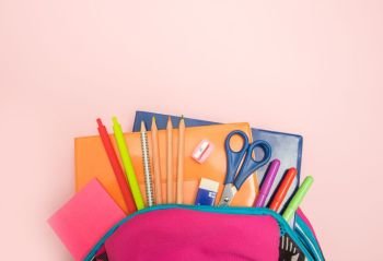 Back to school concept. Backpack with school supplies on colored background