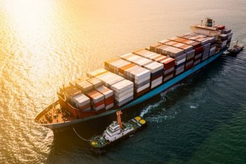Logistics and transportation of International Container Cargo ship in the ocean and over the sunset background aerial view from drone 