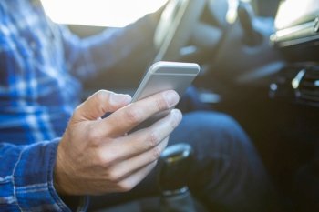 Close Up Of Man In Car Texting On Mobile Phone Whilst Driving
