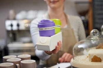 Close Up Of Female Worker in Cafe Serving Takeaway Coffee In Recycled Holder Made From Used Carton 