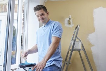 Portrait Of Man Stirring Paint Before Decorating Room At Home