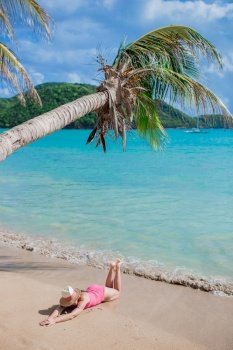 Relaxing and enjoying on summer vacation, woman lying on sandy beach. Young woman on a tropical beach with hat