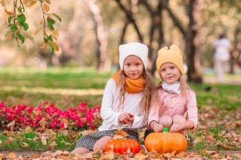 Little adorable girls with pumpkin outdoors on a warm autumn day. Portrait of kids in fall on october. Little adorable girls with pumpkin outdoors on a warm autumn day.