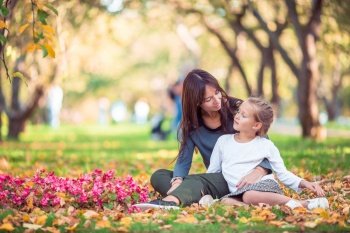 Young mother with cute little girl in autumn park on sunny day. Family enjoy warm weather at september day. Little girl with mom outdoors in park at autumn day