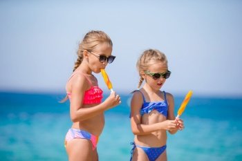 Happy little girls eating ice-cream during beach vacation. People, children, friends and friendship concept. Happy little girls eating ice-cream during beach vacation.
