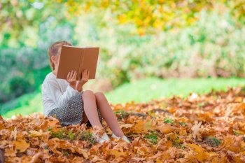 Portrait of adorable little girl outdoors at beautiful warm day with book in fall. Portrait of adorable little girl outdoors at beautiful warm day with yellow leaf in fall
