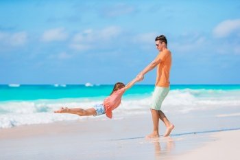 Happy father and his adorable little daughter at white sandy beach. Little girl and happy dad having fun during beach vacation