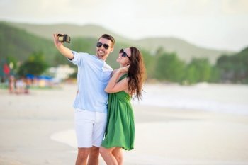 Happy couple taking a selfie photo on white beach. Two adults enjoying their vacation on tropical exotic beach. Happy couple taking a photo on white beach on honeymoon holiday