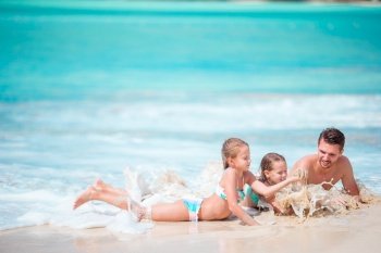 Father and kids enjoying beach summer vacation. Father and little kids enjoying beach summer tropical vacation playing in shallow water