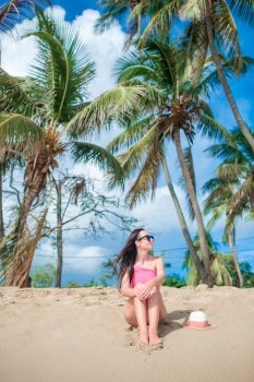 Young happy woman in swimsuit on white beach. Young slim woman on tropical beach under the palm tree in shallow water
