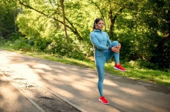 Morning fitness training in park, woman in headphones running on walkway. Female runner goes in for sports at sunny day, healthy lifestyle, jogger on outdoors workout. Fitness training in park, woman in headphones