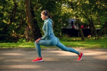 Morning fitness training in park, woman in headphones doing exercise on walkway. Female runner goes in for sports at sunny day, healthy lifestyle, jogger on outdoors workout. Woman in headphones doing exercise on walkway