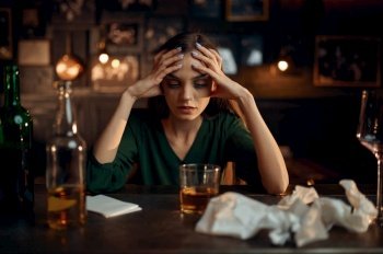 Drunk depressed woman drinks alcohol beverage at the counter in bar. One female person in pub, human emotions, leisure activities, nightlife. Drunk depressed woman at the counter in bar