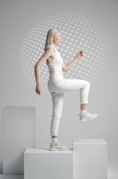 Futuristic young woman in white clothes stands on cube, light background. Female person in virtual reality style, future technology, futurism concept, cyber or robot theme. Futuristic young woman stands on cube, futurism