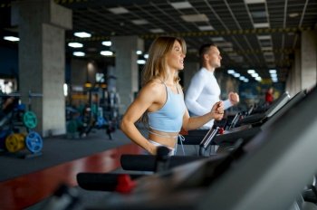 Sportive couple on the treadmill, fitness training in gym. Athletic man and woman on workout in sport club, active healthy lifestyle, physical wellness. Sportive couple on the treadmill, training in gym