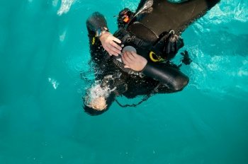Male diver in scuba gear poses in pool, top view, course in diving school. Teaching people to swim underwater, indoor swimming. Man with aqualang. Male diver in scuba gear poses in pool, top view