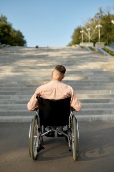 Man in wheelchair at the stairs, back view, handicap problem. Paralyzed people and disability, handicap overcoming. Helpless disabled male person walking in park. Man in wheelchair at the stairs, back view