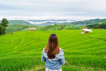 Young woman traveler on vacation enjoying and looking at beautiful green rice terraces field in Pa Pong Pieng, Chiangmai Thailand
