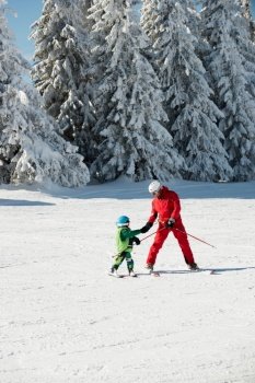 Ski trainer giving hand to little boy
