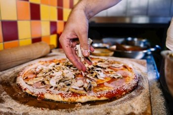 Chef putting mushrooms on pizza in pizza restaurant. Pizza Making Process.