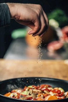 Chef sprinkling oregano over vegetables in a pan, motion blur . Seasoning - Chef Sprinkling Oregano over Vegetables 