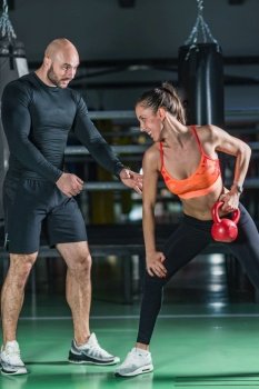 Personal trainer exercising with kettlebell with woman in the gym