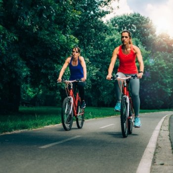 Two Women Riding Bicycles Together in Park