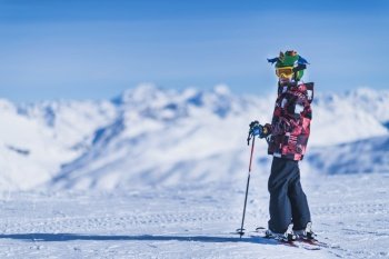Young male skier in colorful outfit on top of mountain ski resort. Copy space for text.. Skiing Boy on a Mountain Top