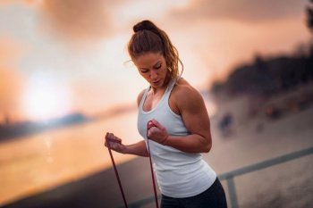 Woman Exercising Outdoors with Elastic Resistance Band, by the Lake . Woman Exercising with Rubber Resistance Band by The Lake 