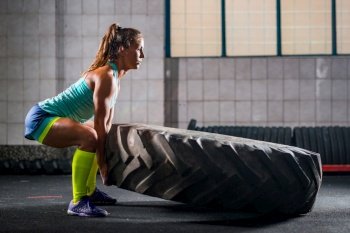 Woman athlete exercising with tire