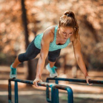 Woman Exercising on Parallel Bars Outdoors in The Fall, in Public Park