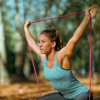 Woman Exercising Squats With Elastic Band Outdoors in The Fall, in Public Park